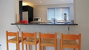 Eine Küche mit Mikrowelle, Kaffeemaschine und einem Stuhl.