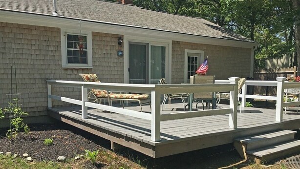 A house with a wooden deck, a flag, and outdoor furniture. - Quiet 3BR Ranch - Little Dog Friendly! (2033) (Harwich)