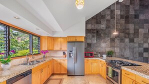 Eine moderne Küche mit Holzschränken, Granit-Arbeitsplatten, einem Edelstahl-Kühlschrank, einer Mikrowelle, einem Gasherd und einem Geschirrspüler.
