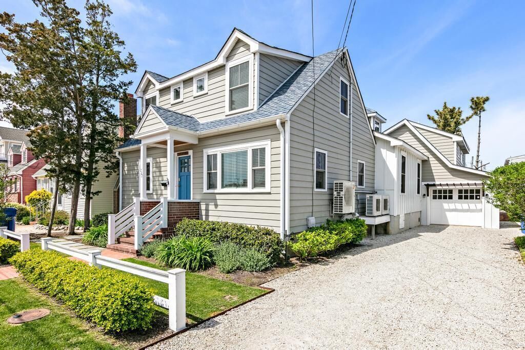 A two-story house with a front porch, a covered entryway, and a gravel driveway.
