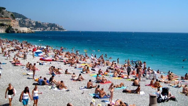 En fullsatt strand med folk som solar och badar.