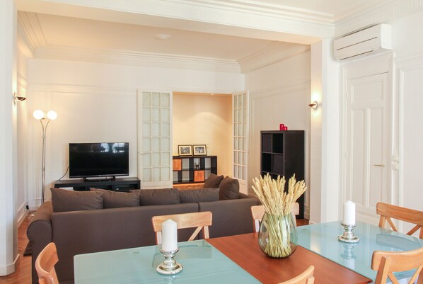 A living room with a sofa, TV, and a dining table with chairs.