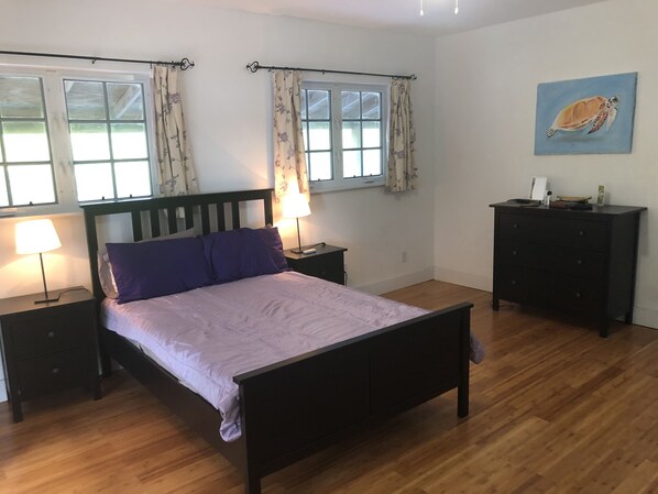 A bedroom with a bed, two bedside tables, a dresser, and a window with curtains. - 4 Double Beds Water Front On Bone Fish Flats 10 min drive to George Town Exuma (george town)