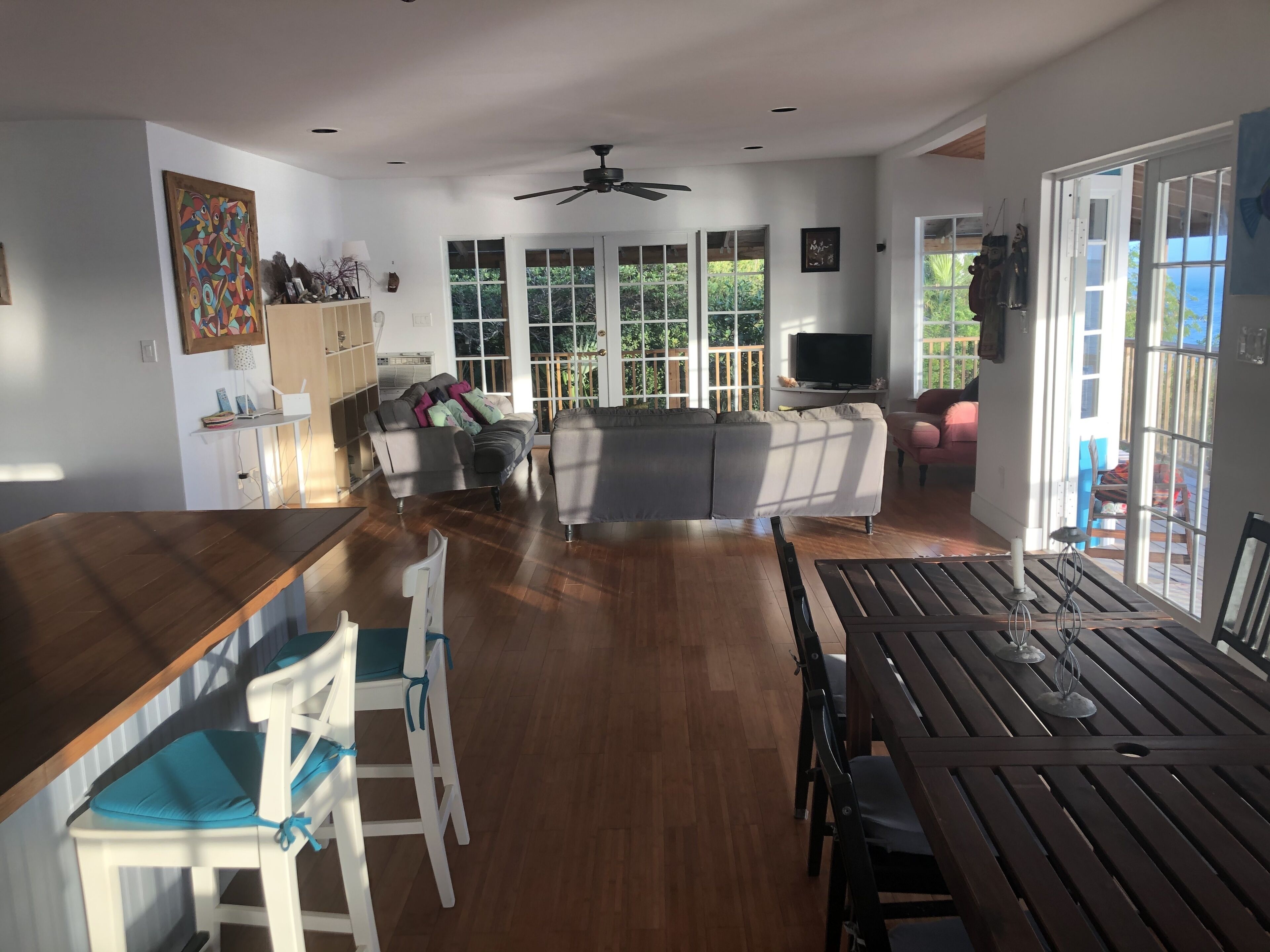 A spacious living area with a wooden dining table, a sofa, and a TV.