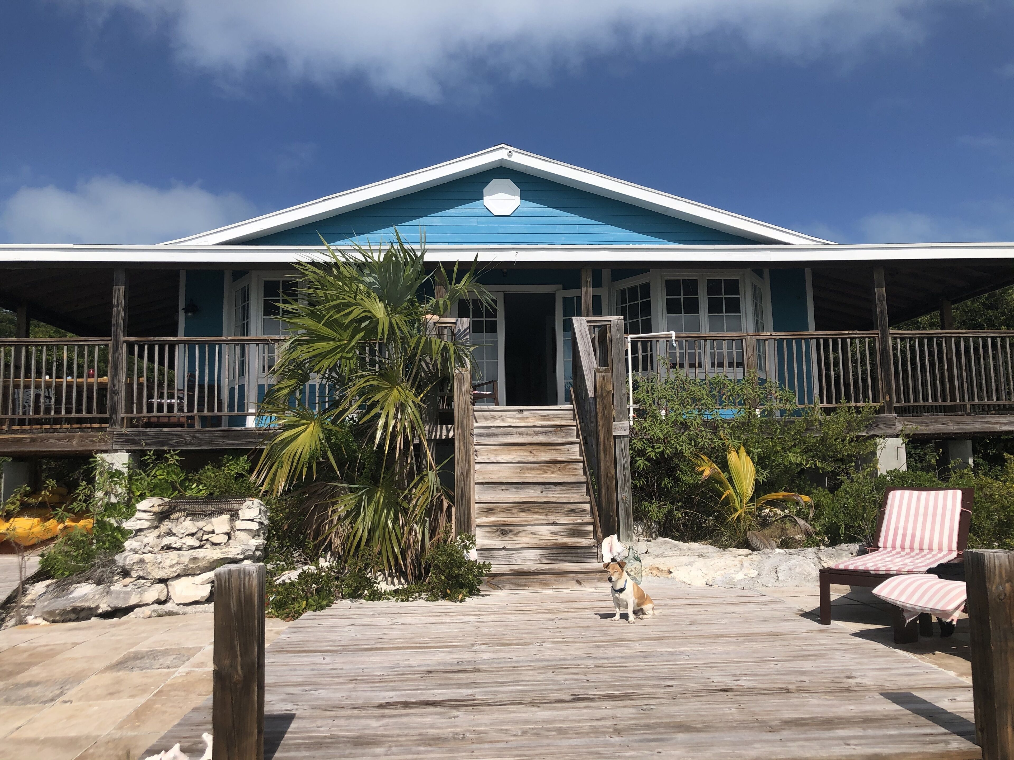 A beachfront property with a wooden deck, a covered porch, and a pool area.