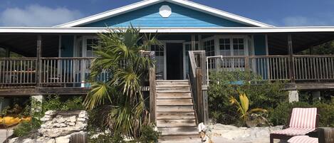 A beachfront property with a wooden deck, a covered porch, and a pool area.