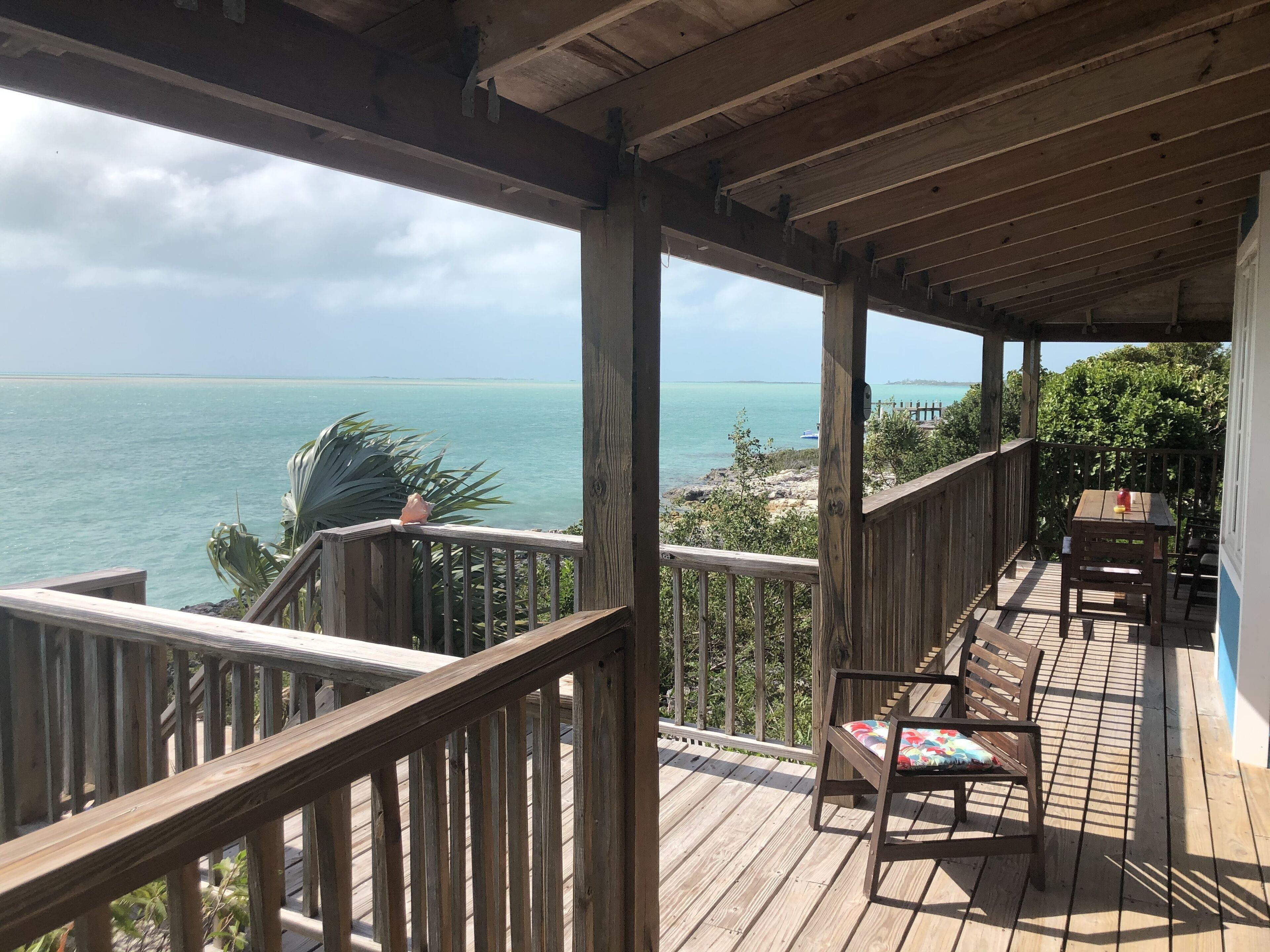A wooden deck with a railing overlooking a beach and ocean.