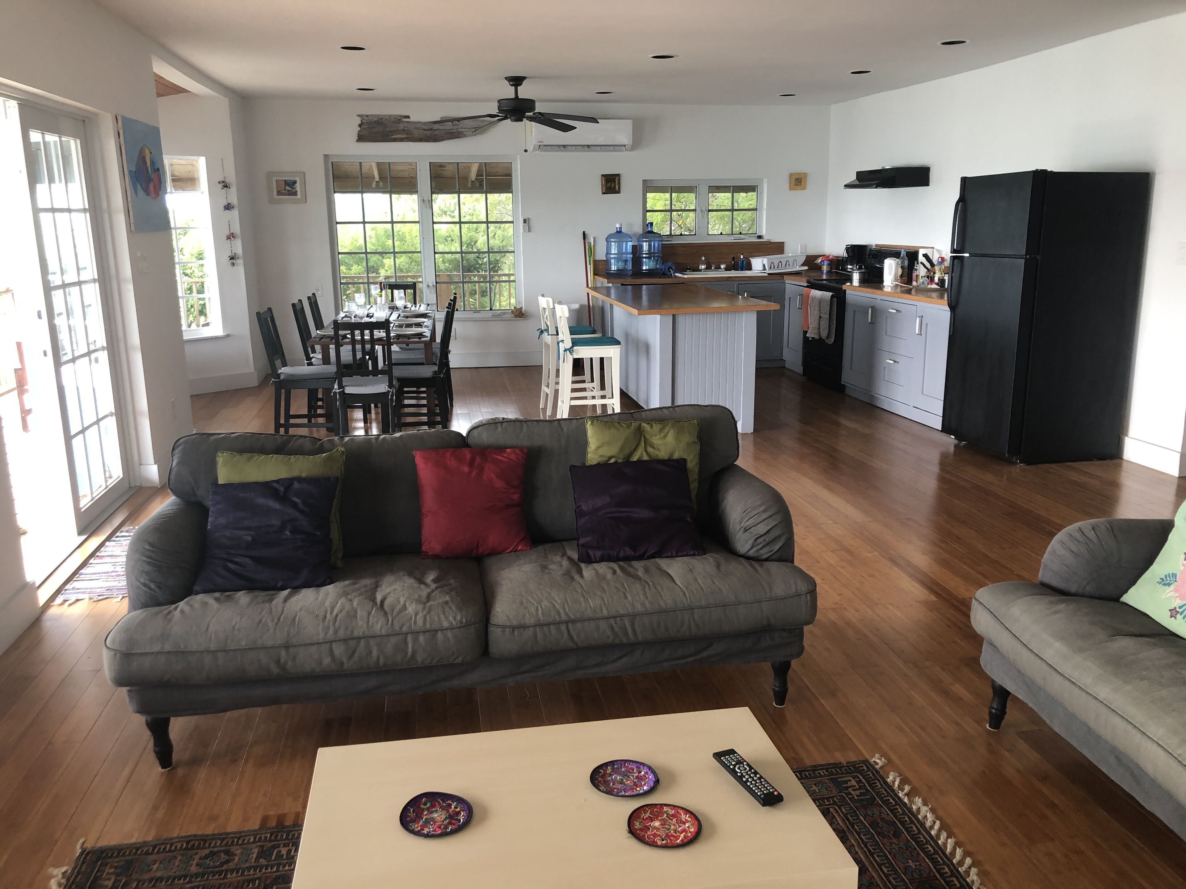 A spacious living area with a grey sofa, a coffee table, and a dining area with chairs and a table.
