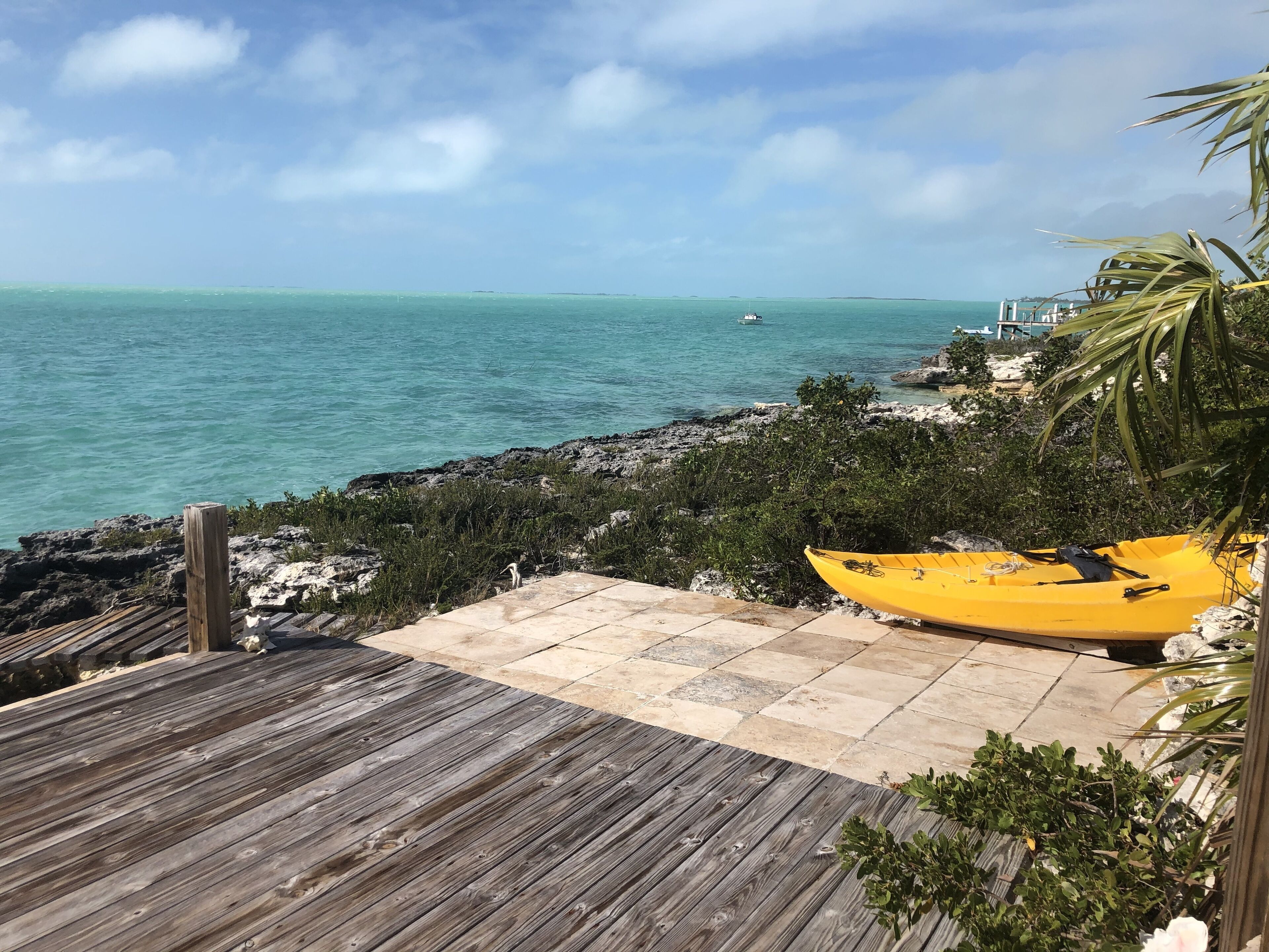 A wooden deck leading to a rocky shoreline with a yellow kayak.