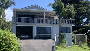 A two-story house with a garage, a balcony, and a well-maintained lawn. - Teaghlach: Tapeka / Russell Holiday Home (Tapeka Point (Russell))