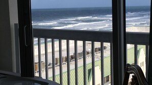A balcony with a view of the ocean and a building with green roofs. - Beautiful 9th floor OceanView Studio Condo  - Pool is OPEN! (Daytona Beach)