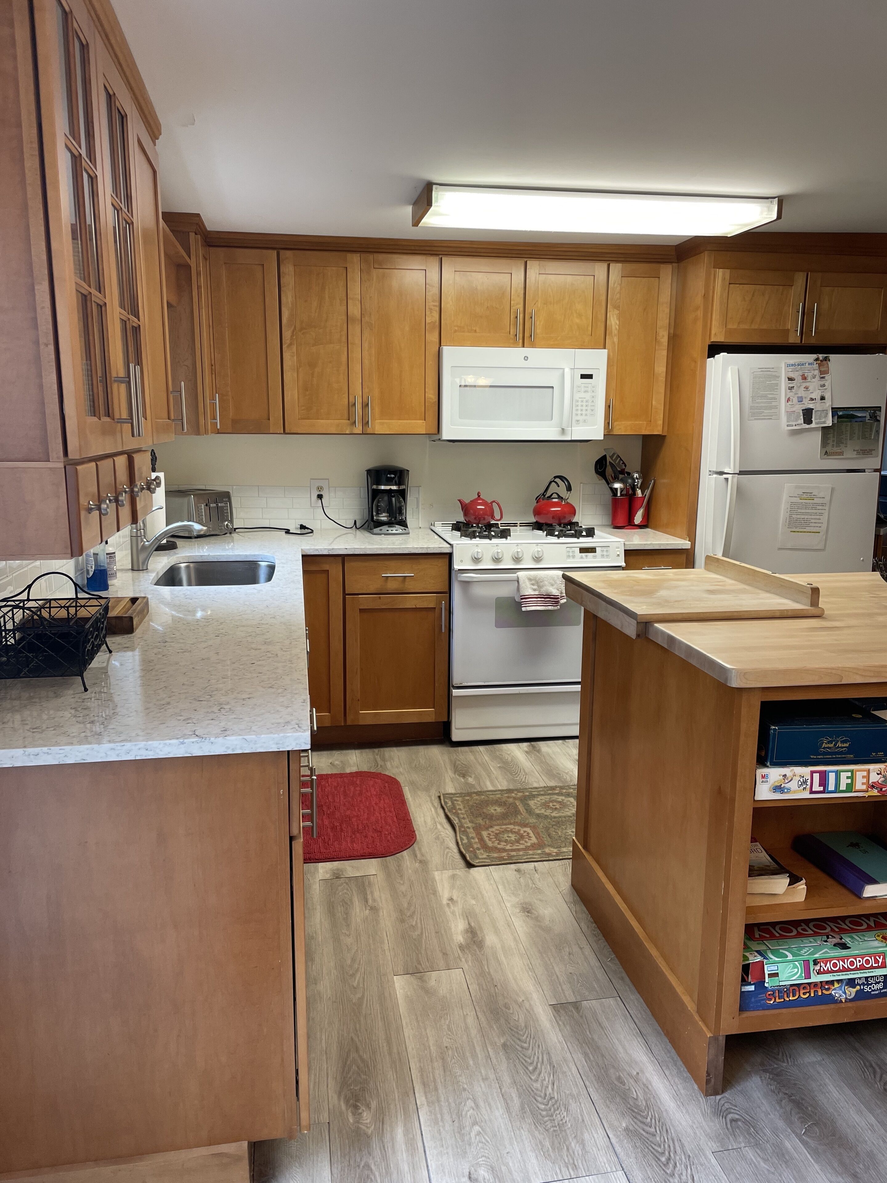 A kitchen with wooden cabinets, a white microwave, a stove, and a refrigerator.