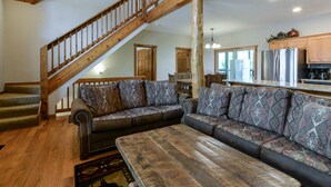 A spacious living room with a wooden staircase, a large sectional sofa, and a wooden coffee table.