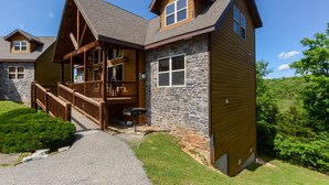 A lodge with a stone facade, wooden deck, and a stone chimney.