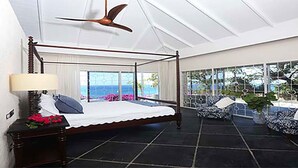 A bedroom with a four-poster bed, a ceiling fan, and a view of the ocean through large windows. - Ultimate Caribbean Getaway: 3 beaches, Cook, Housekeeper & Valet, 24x7 Concierge (Gros Islet)
