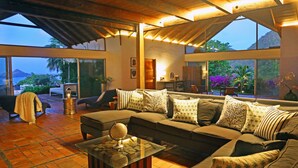 A spacious living area with a large sofa, a coffee table with a globe, and a fireplace. There are large windows offering a view of the outdoors. - Ultimate Caribbean Getaway: 3 beaches, Cook, Housekeeper & Valet, 24x7 Concierge (Gros Islet)
