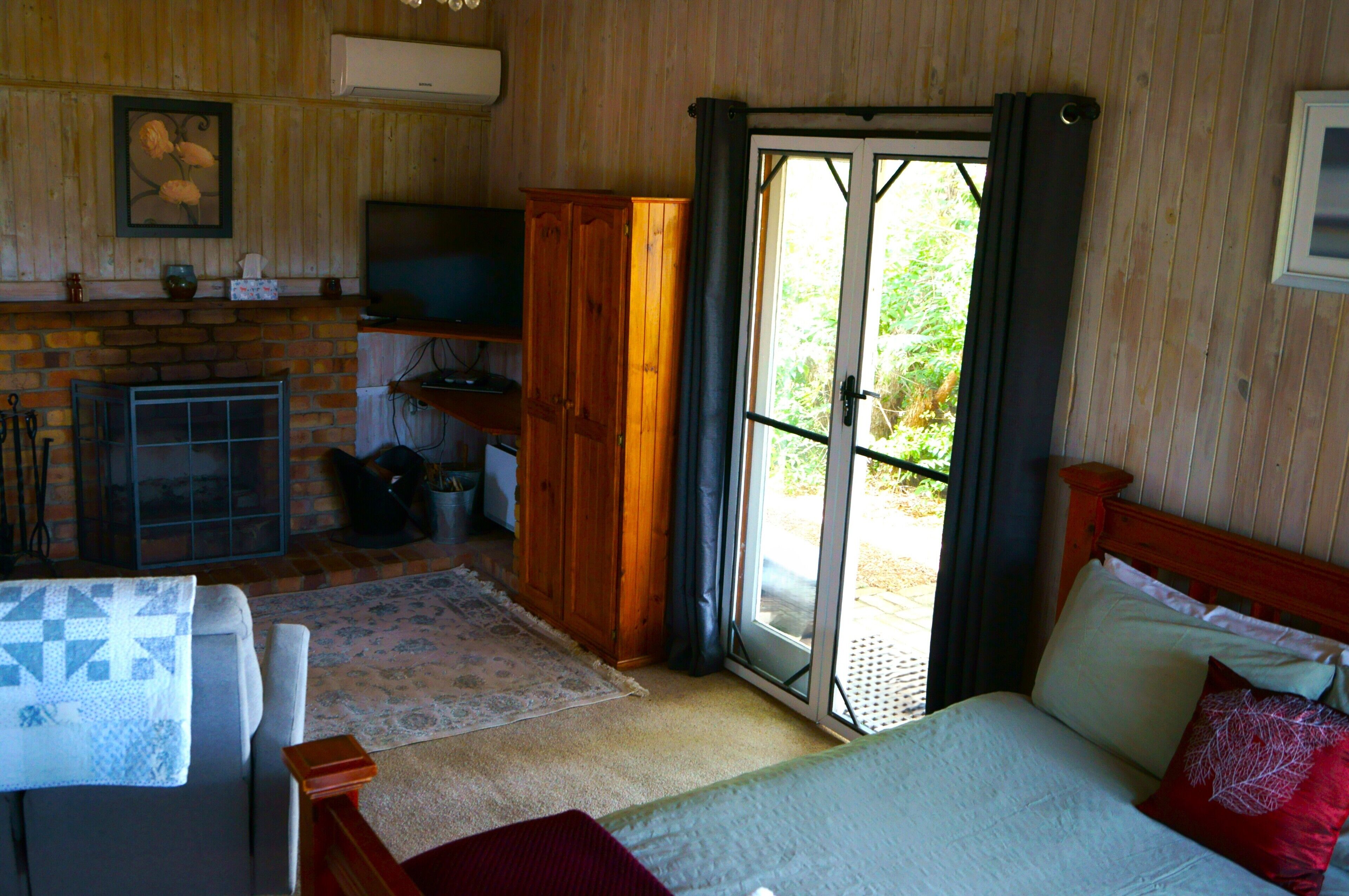 Ein gemütliches Zimmer mit einem Bett, einem kleinen Tisch, einem Fernseher, einem Kamin und einer Glastür zum Außenbereich.