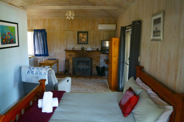 Une pièce confortable avec un lit, une petite table, une chaise, une cheminée et un téléviseur.