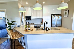 A modern kitchen with a central island, stainless steel appliances, pendant lighting, and a view of the outdoors.