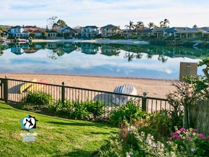 A beachfront property with a pool, a fenced area with beach chairs, and a logo indicating pet-friendly accommodation. - Holiday Home with Private Beach & Stunning Views! (Encounter Bay)