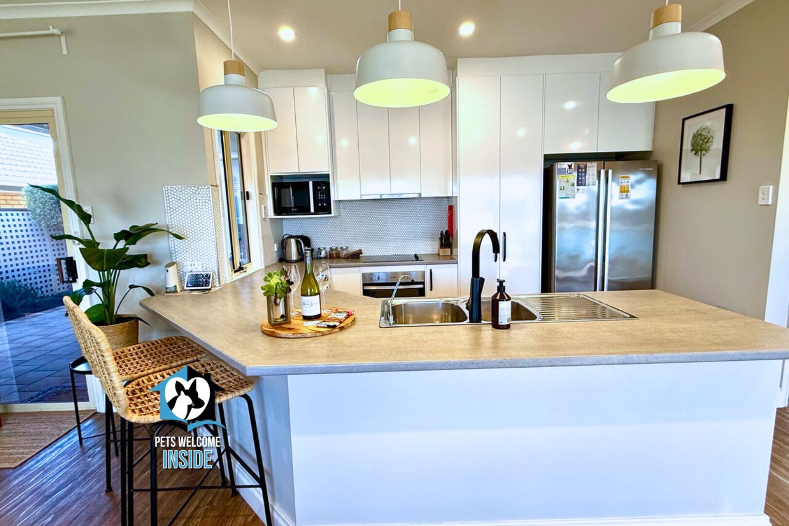 A modern kitchen with a central island, pendant lighting, and stainless steel appliances.