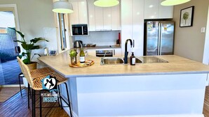A modern kitchen with a central island, pendant lighting, and stainless steel appliances. - Holiday Home with Private Beach & Stunning Views! (Encounter Bay)
