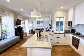 A modern kitchen with a central island, white cabinetry, and pendant lighting.