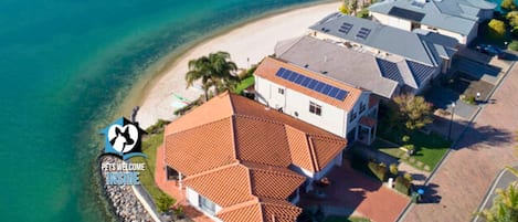 Vista aerea di una zona residenziale costiera con case, una spiaggia e un mare blu cristallino.