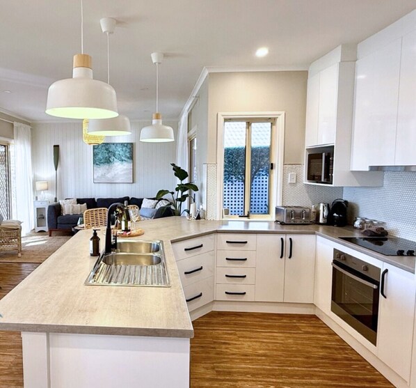 A modern kitchen with a central island, white cabinetry, and a large window.