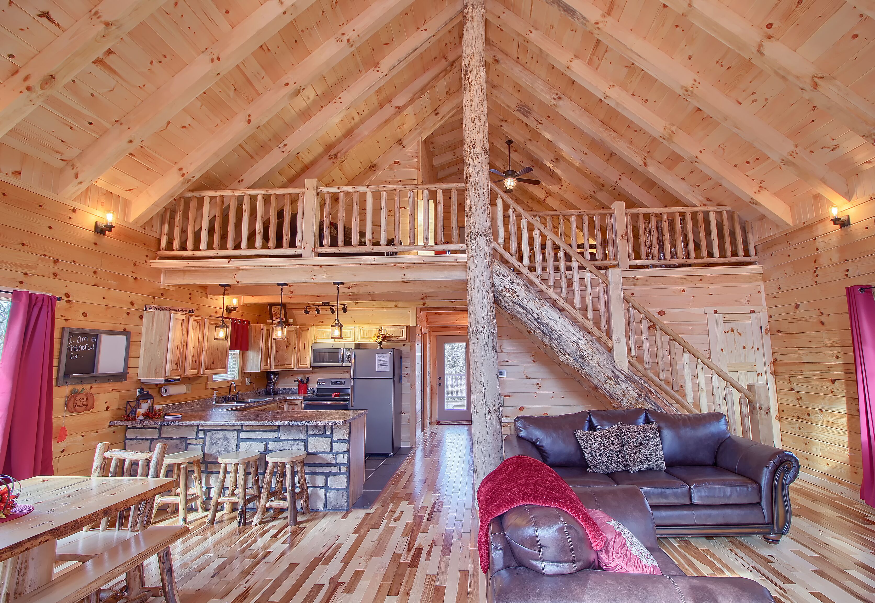 A spacious log cabin with a loft bedroom, a dining area, and a kitchen.