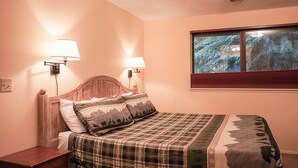 A bedroom with a bed, two wall-mounted lamps, a window with a view of trees, and a wooden headboard. - Emerald Room At Forest House (Pre-packed Breakfast Inc., 1mile from Mt Rainier) (Ashford)