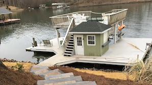 A stone staircase leading to a dock area with a small cabin and outdoor seating. - Charming waterfront home, with central location to area marinas, plus Super Dock (Moneta)