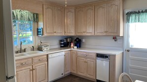 A kitchen with wooden cabinets, a dishwasher, a coffee maker, and a toaster. - Charming waterfront home, with central location to area marinas, plus Super Dock (Moneta)