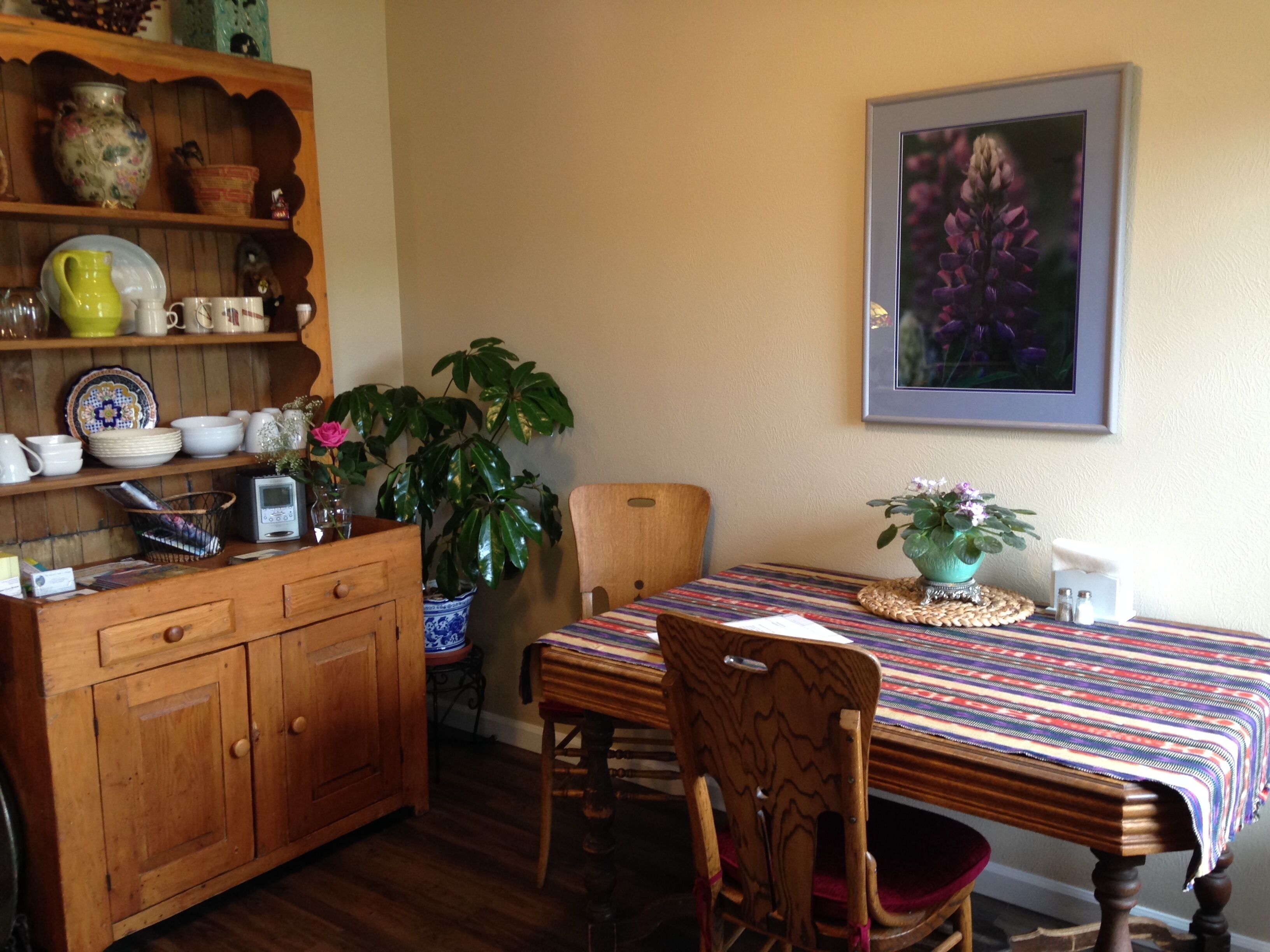 A dining area with a wooden table, chairs, and a bookshelf filled with various items.