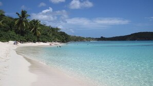 Una playa con aguas turquesas cristalinas, arena blanca y palmeras.