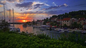 A marina with boats docked, a sunset in the background, and buildings with red roofs.