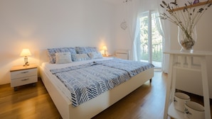 A bedroom with a bed, nightstands, a lamp, and a window with curtains.