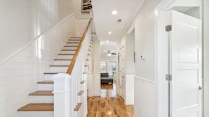 A staircase with wooden steps and white railings leading to a room with a ceiling fan.