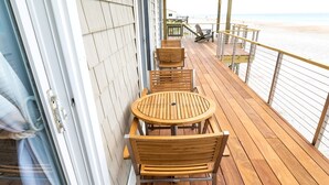 A wooden deck with outdoor seating and a view of the beach.