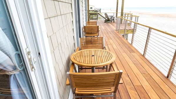 A wooden deck with outdoor seating and a view of the beach.