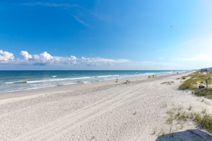 Een strand met een heldere lucht, een rustige zee en enkele mensen en tenten.