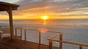 A wooden deck with a railing overlooking a beach at sunset. - Paradise Found - Updated Classic 3 BR Home - Direct Oceanfront! (North Topsail Beach)