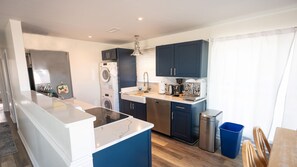A modern kitchen with a central island, built-in appliances, and a dining area with a table and chairs.