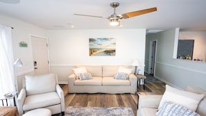 A living room with a beige sofa, two armchairs, a ceiling fan, and a painting on the wall. - Paradise Found - Updated Classic 3 BR Home - Direct Oceanfront! (North Topsail Beach)