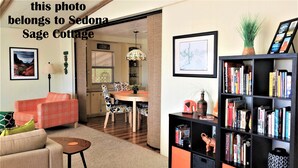 Een woonkamer met een bank, een salontafel, een boekenkast en een eethoek met een tafel en stoelen.