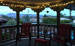 Een overdekte veranda met lichtjes, stoelen en een tafel.