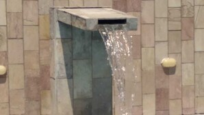 Una fuente de agua con una estructura de piedra rectangular y una piscina delantera.
