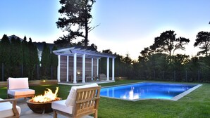 Un cortile con piscina, un braciere e mobili da giardino.