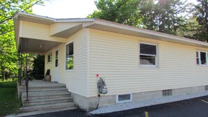 A single-story building with a covered porch, a small front entrance, and a parking area in front.