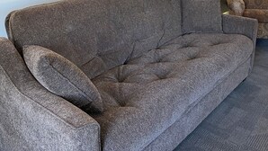 A grey sofa with a clock on the wall.